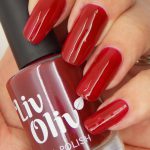 Close up female hand holding LivOliv scarlett red nail polish