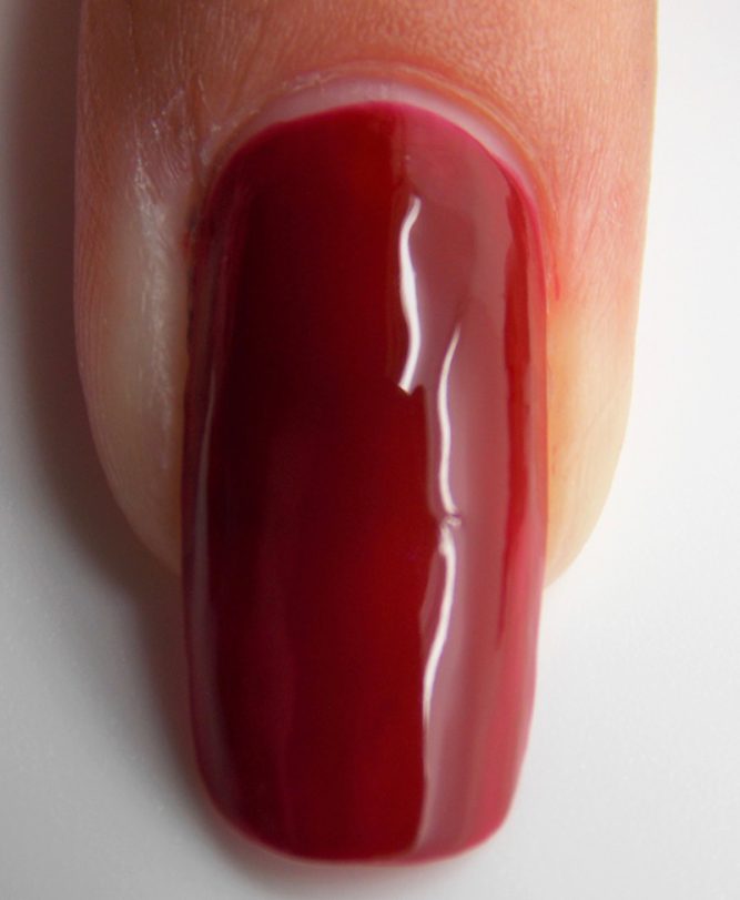 Close up of fingernail with LivOliv Scarlet (deep red) vegan nail polish